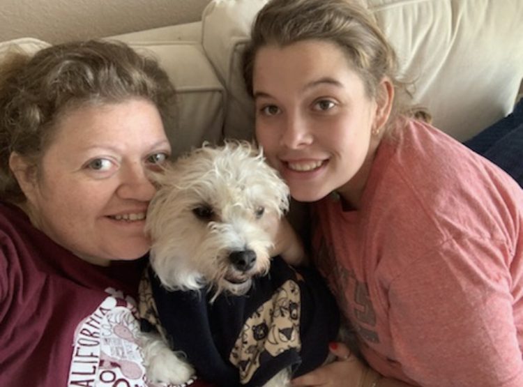 Two women and a dog pose for the camera.