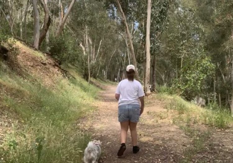 A woman walking her dog down the trail